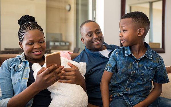 Family with mother using a smart phone to pay her bill