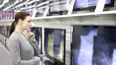 Woman looking at a television in an electronics store.